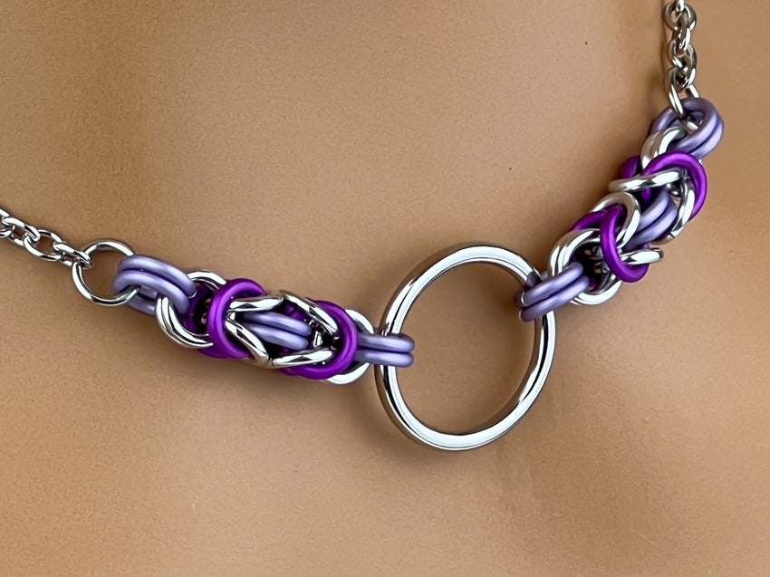 A close-up image of a frost-colored O ring chainmaille necklace with a stainless steel O ring and anodized aluminum links in silver, violet, and purple shades.